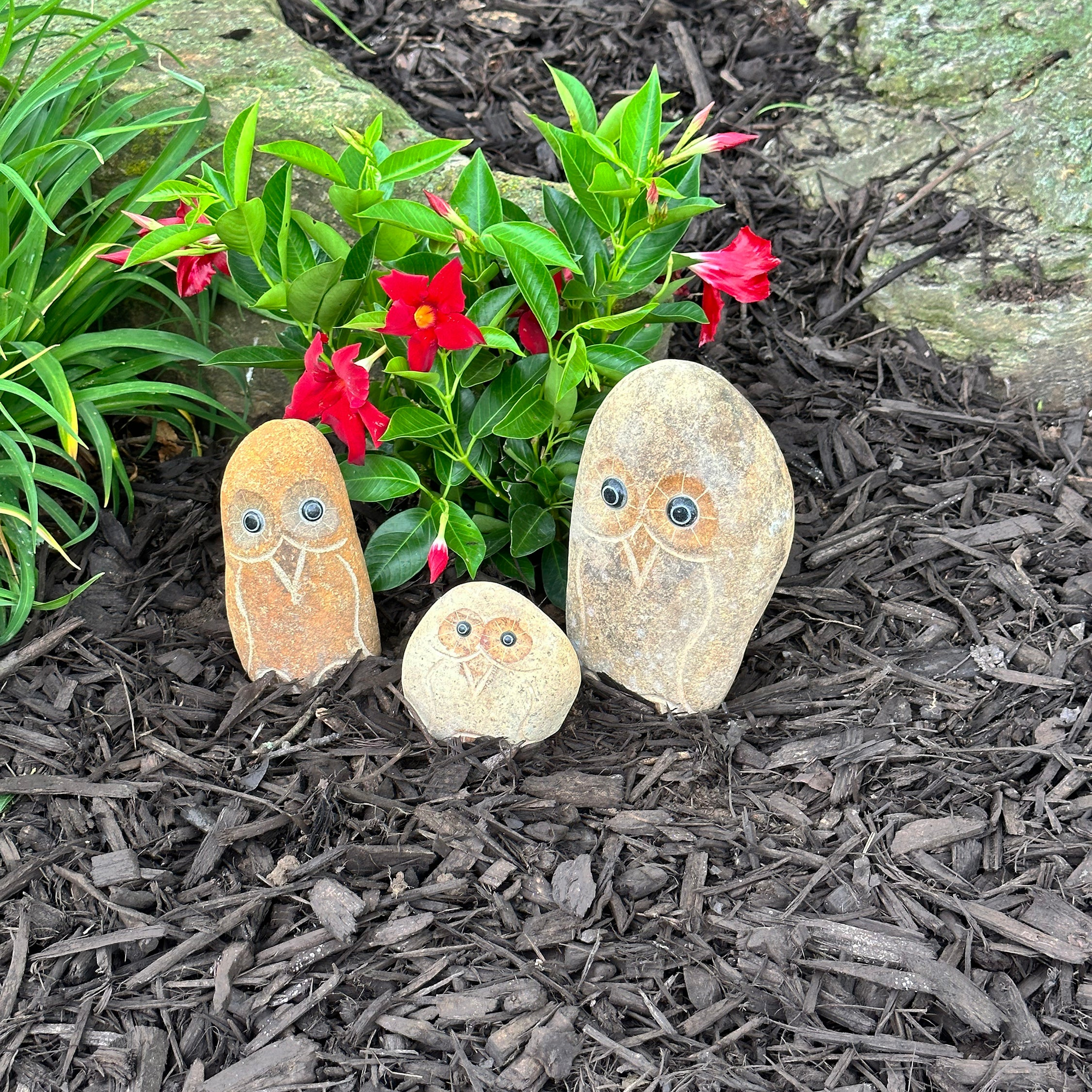 Hand-carved granite boulder stone owl family set with 3 pieces in garden setting.