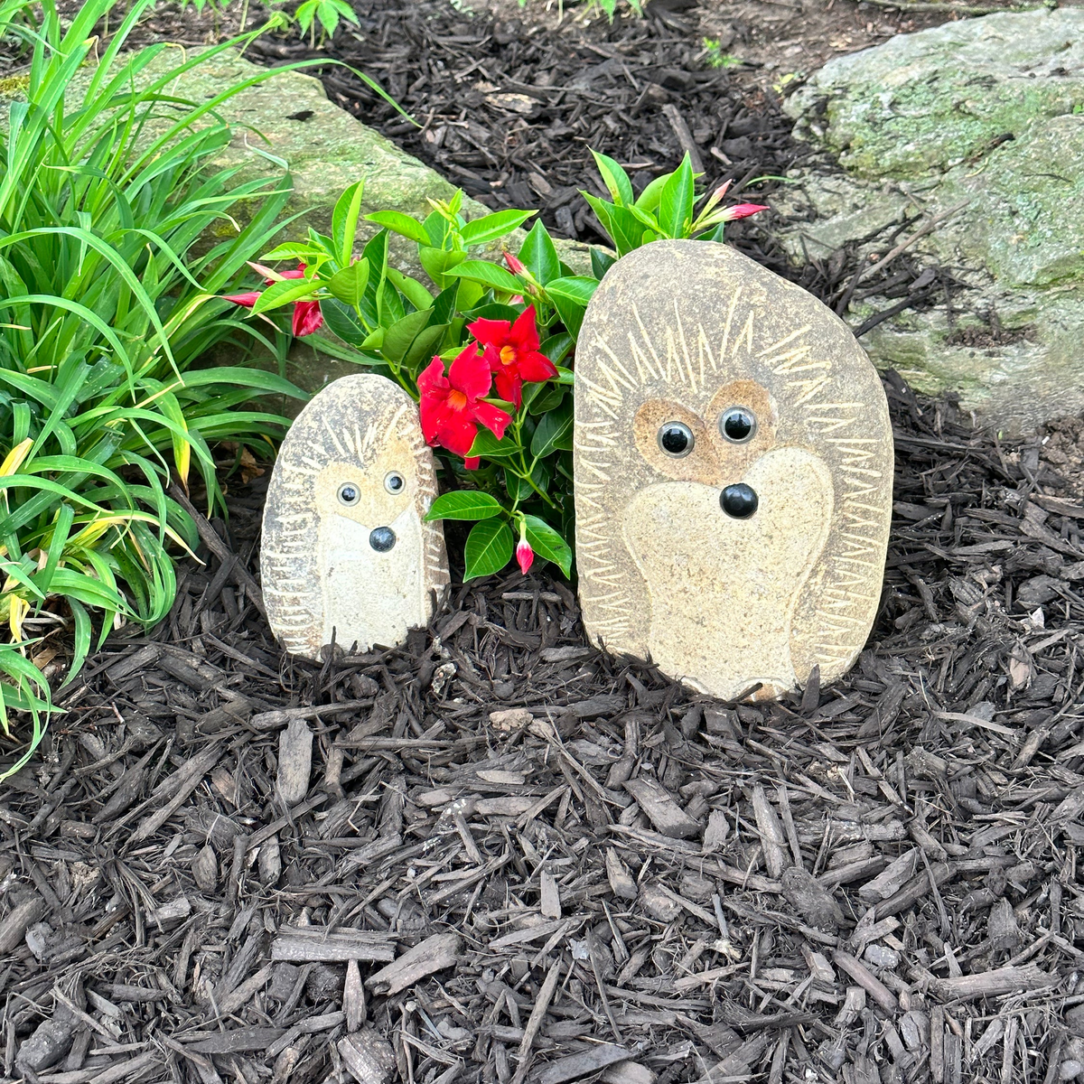 Hand-carved granite stone hedgehogs in a garden setting.