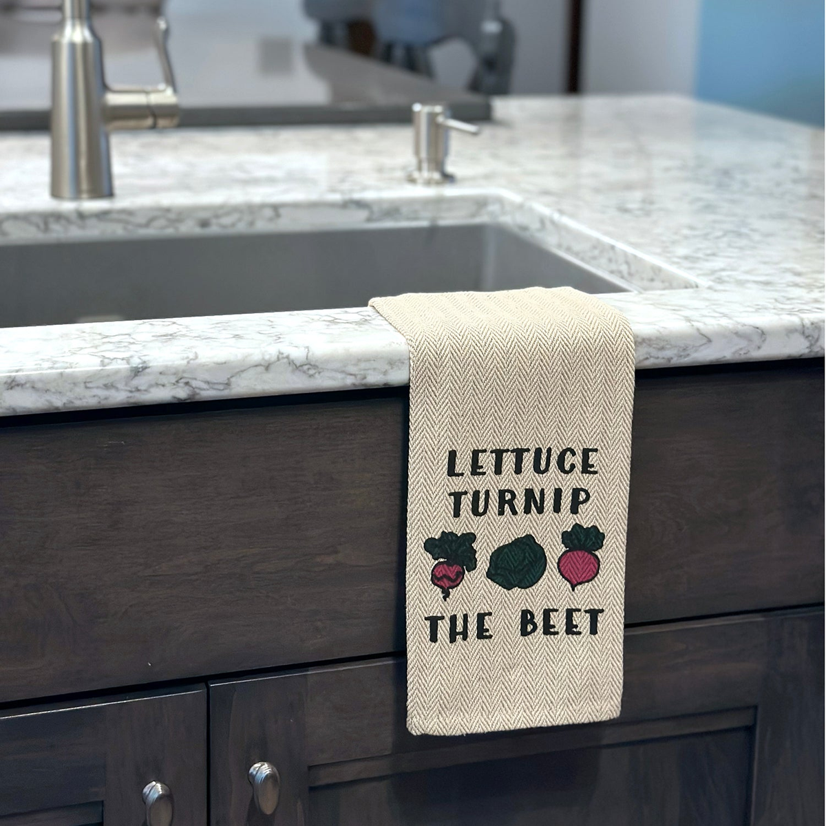 Kitchen tea towel with &quot;Lettuce Turnip the Beet&quot; design on a modern kitchen counter.