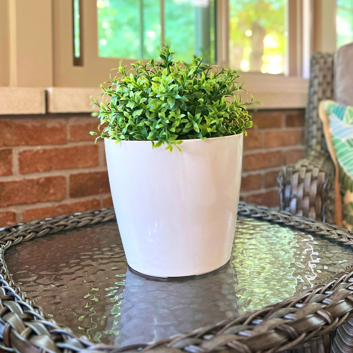 7&quot; cream round bamboo self-watering plant pot on outdoor table with greenery.