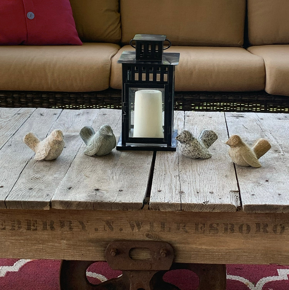 Hand-carved natural granite stone birds in assorted colors on wooden table, sold individually.