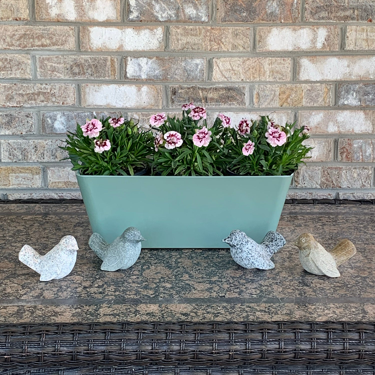 Hand-carved granite stone bird collection in assorted colors, displayed around a planter.