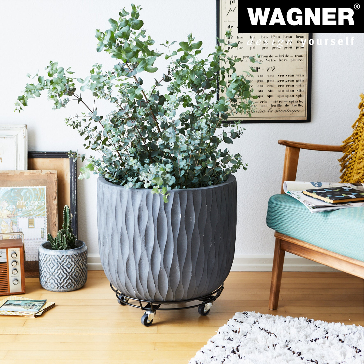 15&quot; black round steel wire indoor plant caddy with caster wheels, supporting a large pot in a living room setting.