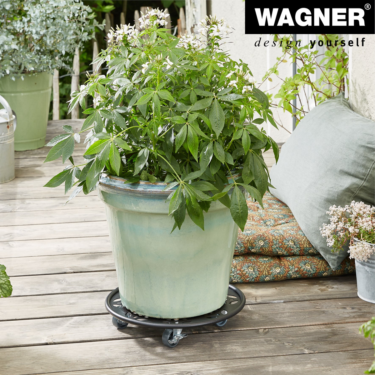 11.8&quot; black round flower design steel plant caddy with brakes, supporting a potted plant on a wooden deck.