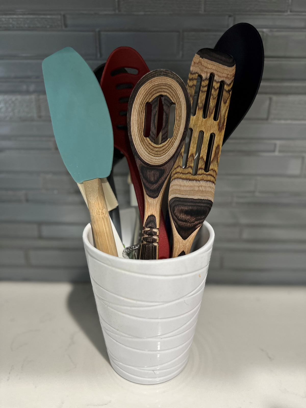 White ceramic pot holding kitchen utensils.