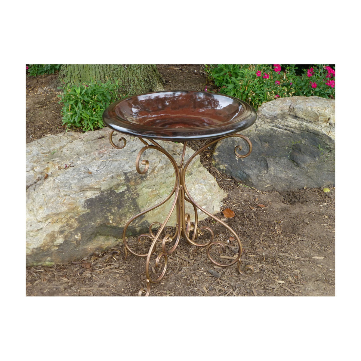 Antique brown fiber clay birdbath top with antique bronze metal stand in a garden setting.