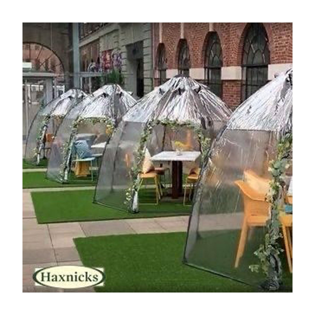 Standard Sunbubble walk-in greenhouse by Haxnicks on grass, dome shape with tables and chairs inside.