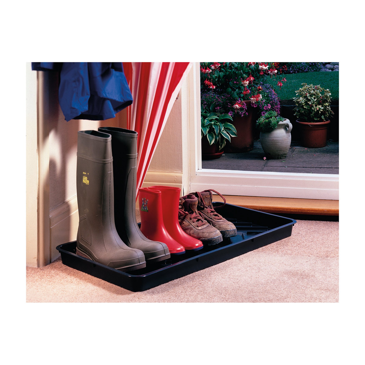 Black boot tray holding various footwear, crafted from recycled polypropylene, ideal for mud scraping and drainage; dimensions 31&quot;L x 16&quot;W x 2&quot;H.