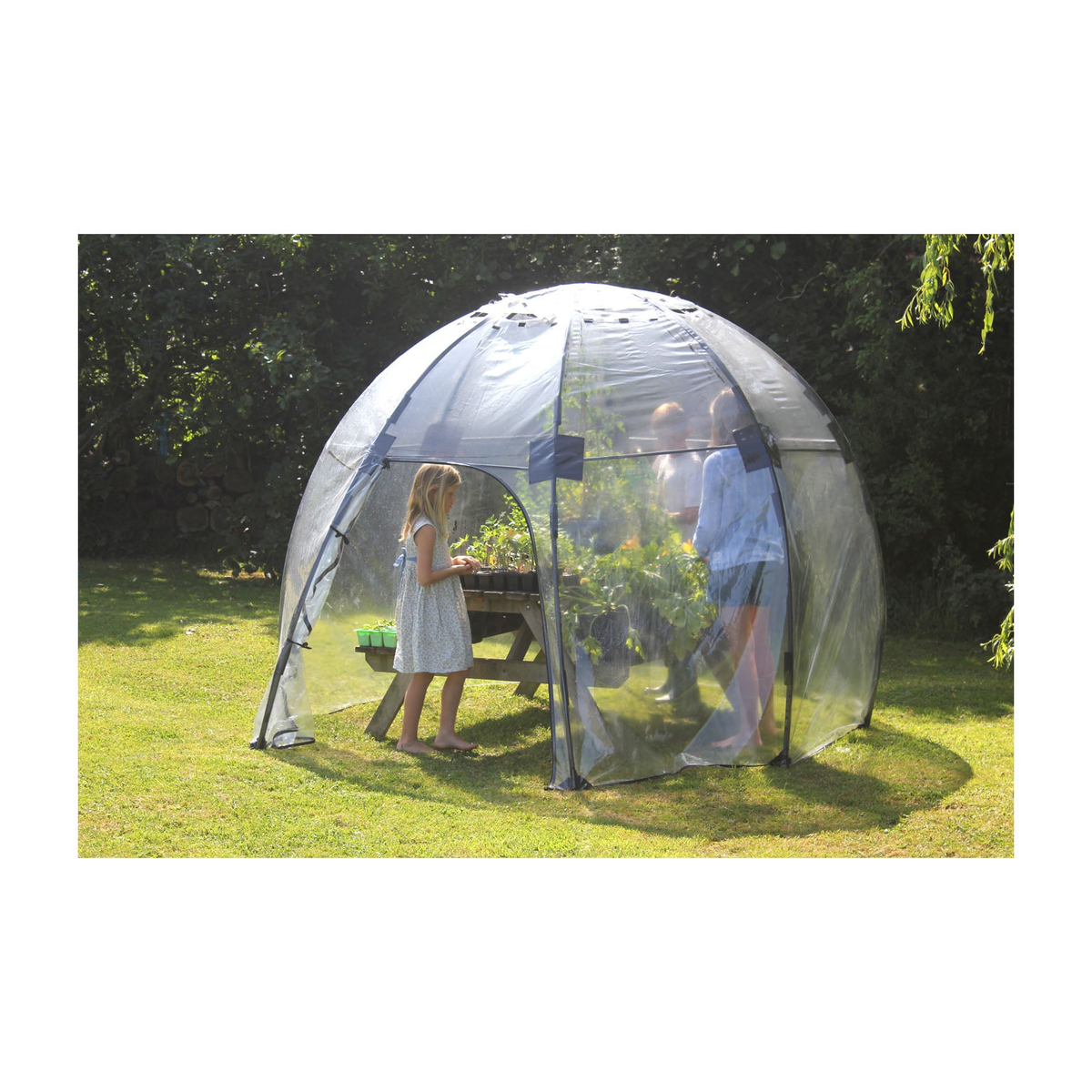 Standard Sunbubble Walk-In Greenhouse in a garden setting, featuring UV-stabilized PVC and fiberglass construction with adjustable vents and a zippered doorway.