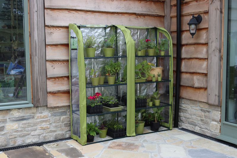 Double Light-Booster Plant House with green potted plants, reflective interior, and front panels rolled up.