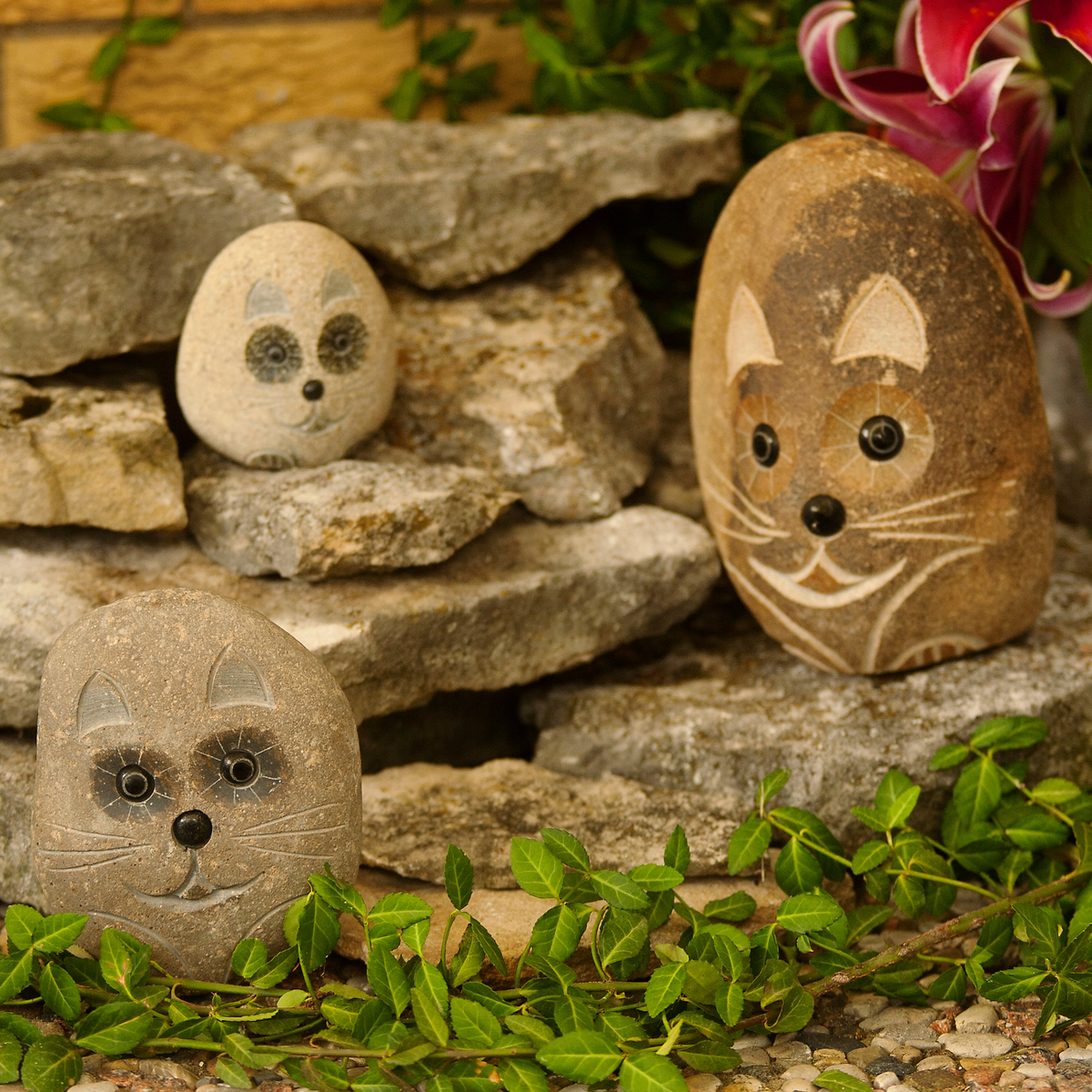 Hand-carved granite boulder stone cat statues in garden setting, three sizes: 4&quot;, 6&quot;, and 8&quot;.