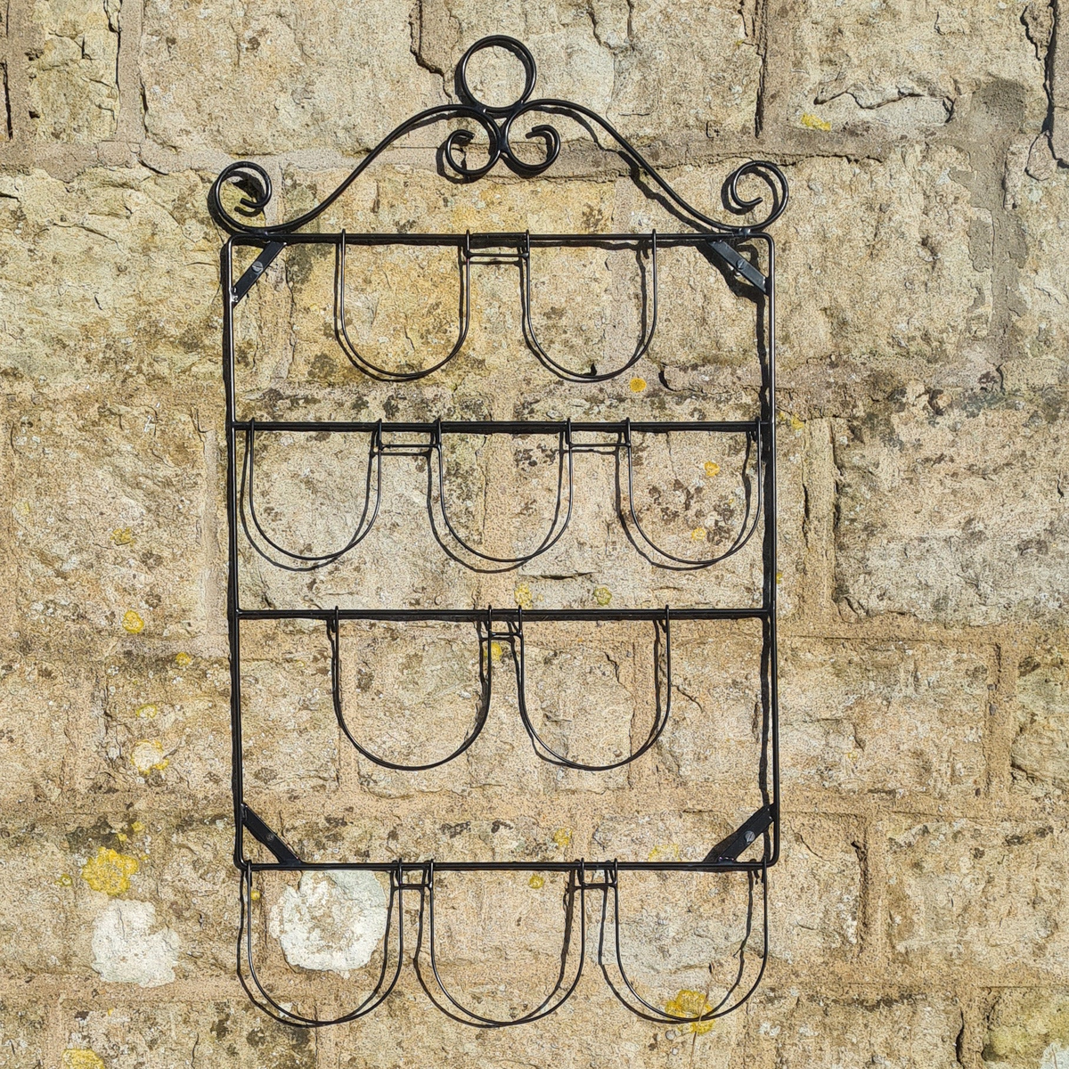 Italian style wall plant holder made of powder-coated steel for 10 pots, mounted on stone wall.