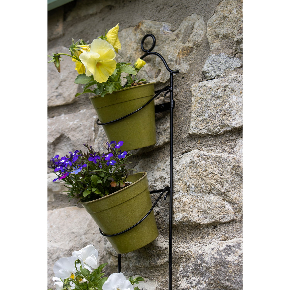 Tall Wall Plant Holder with pots against stone wall, crafted from powder-coated steel, ideal for vertical gardening.