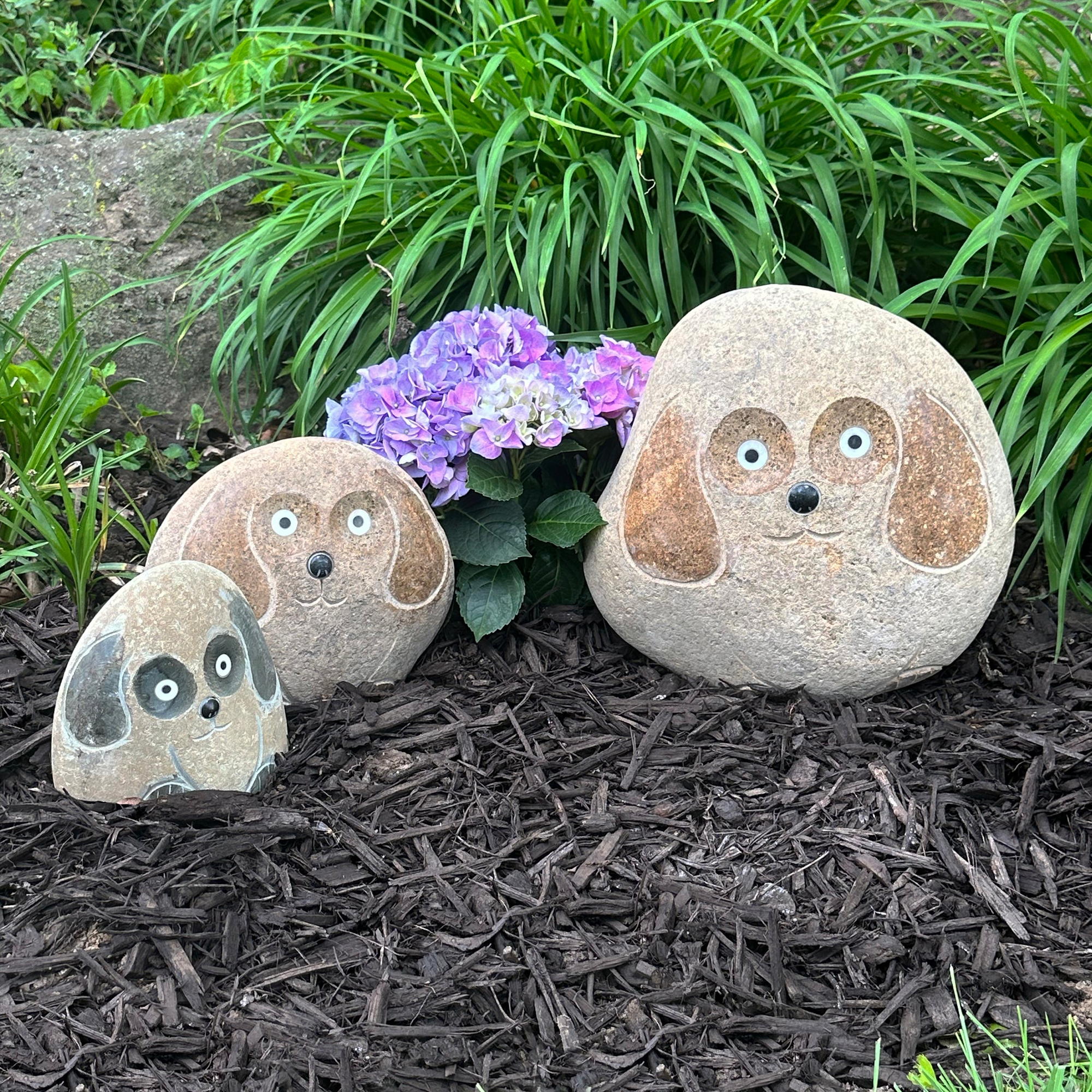 Hand-carved natural granite boulder stone dogs set in garden setting, featuring three sizes.