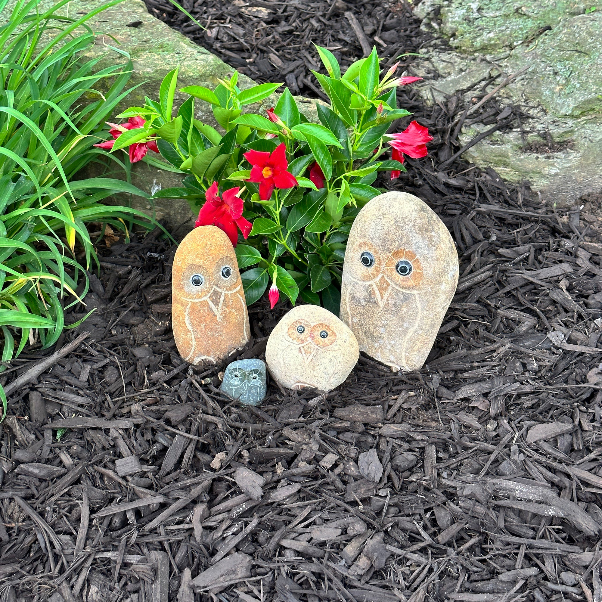 Hand-carved natural granite stone owl family in a garden.