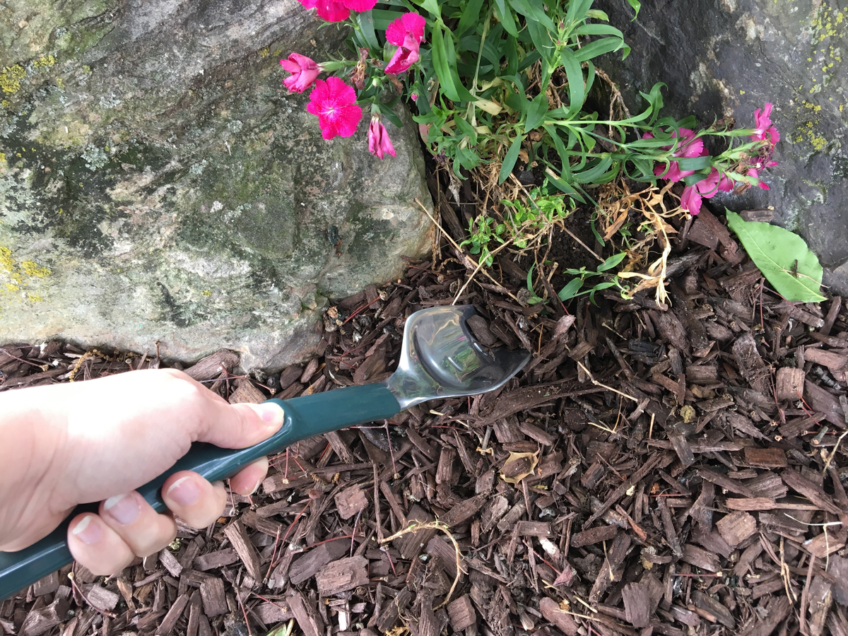 Gardening Kneeler Seat with Trake tool digging soil near flowers.