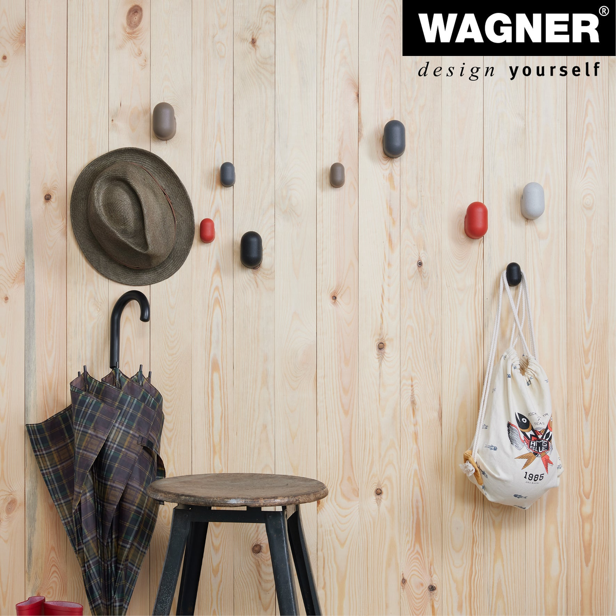 Black Pill Design Multipurpose Wall Hooks 4 Pack by WAGNER on wooden wall, organizing hats and bags.